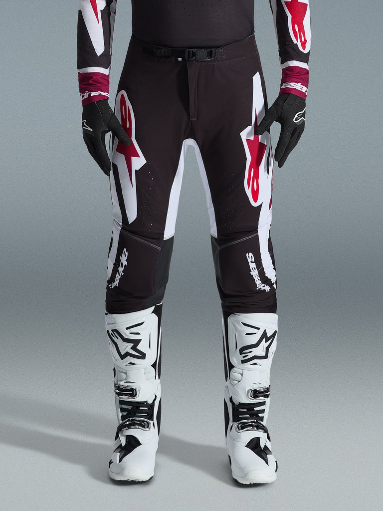 Alpinestars 2026 Supertech AFD Vista Pants, Motocross Pants, Black Red and White, featuring large graphic logos on the thighs and knees, worn with white racing boots and black gloves, athletic race-ready design for elite off-road competition