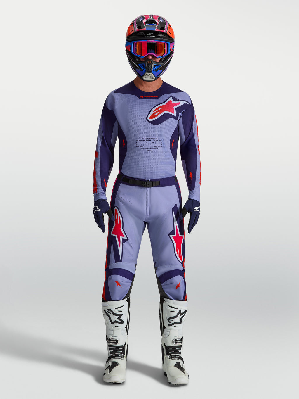 Alpinestars Racer Air Hunt Broek, heren motorcrossbroek in lichtpaars en roze, geventileerd mesh voor optimale luchtstroom, gedragen door een model met bijpassende jersey en witte motorlaarzen, professionele off-road uitrusting.