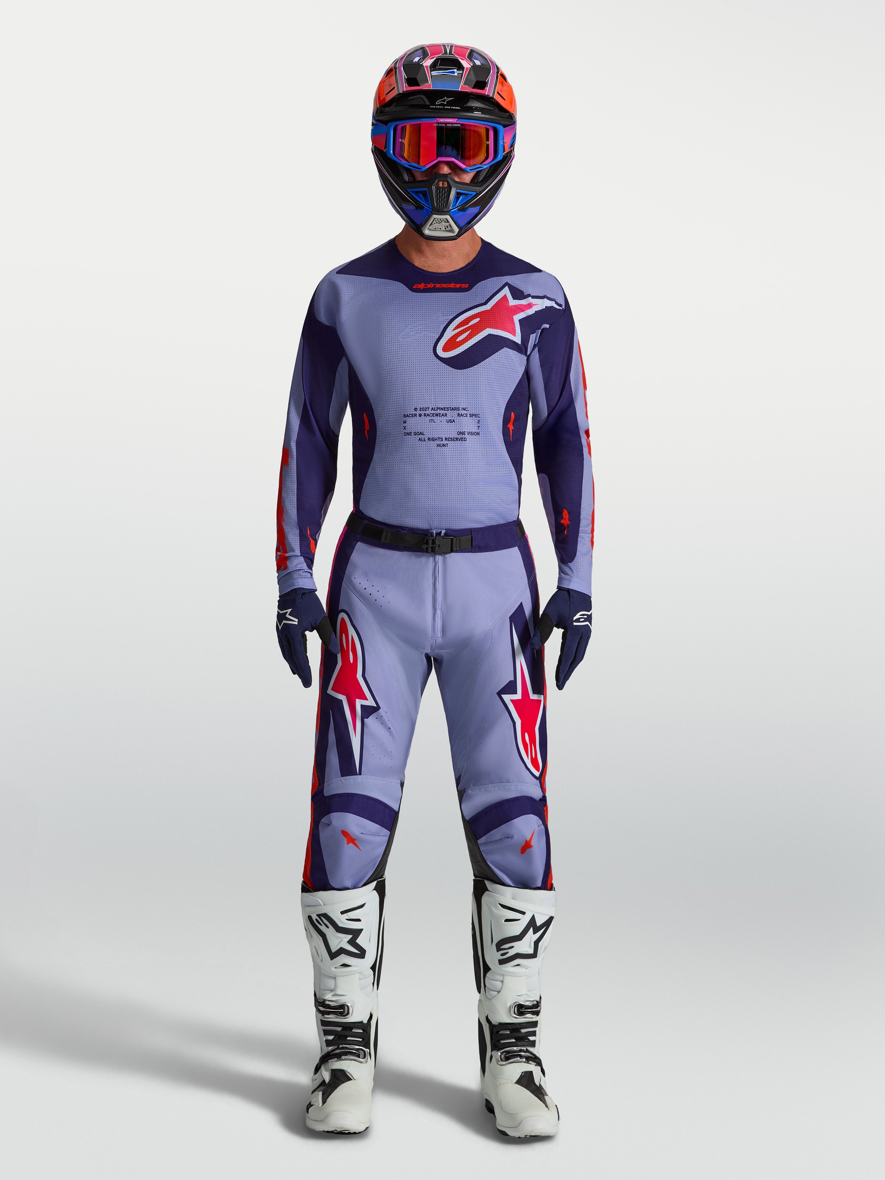Alpinestars Racer Air Hunt Broek, heren motorcrossbroek in lichtpaars en roze, geventileerd mesh voor optimale luchtstroom, gedragen door een model met bijpassende jersey en witte motorlaarzen, professionele off-road uitrusting.