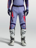 Alpinestars Racer Air Hunt broek, motorcrossbroek voor heren, lichtviolet en paars met roze fluo accenten, gedragen met witte motorlaarzen, geventileerd ontwerp.