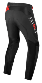 Alpinestars Supertech Foster broek, motorcrossbroek, zwart met witte verticale ASTARS-branding en rode ster-logo's, hoogwaardige textielconstructie met mesh-panelen voor ventilatie en bewegingsvrijheid.