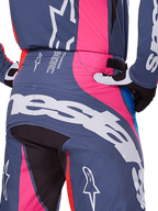Alpinestars 2025 Techstar Dreem Hose, Motocross-Hose, Grau Mehrfarbig mit pinkfarbenen und weißen Akzenten, Rückansicht mit großem Alpinestars-Branding am Gesäß und technischem Spezifikationstext am Bund, getragen als koordiniertes Renn-Ausrüstungsset.