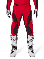 Alpinestars 2025 Techstar Dreem Hose, Motocross-Hose, leuchtendes Rot und Schwarz, mit kantigen Mustern und lasergeschnittenen Belüftungslöchern, getragen mit weißen Motocross-Stiefeln und passenden Handschuhen für Offroad-Rennen