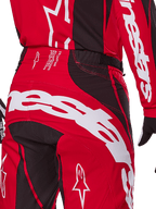Alpinestars 2025 Techstar Dreem Hose, Motocross-Hose, Hellrot und Schwarz, Nahaufnahme des hinteren Taillen- und Gesäßbereichs mit auffälligem weißem Alpinestars-Branding, schwarzen Stretch-Einsätzen und technischem Produktionstext am Bund, entwickelt für Performance im Offroad-Rennsport.
