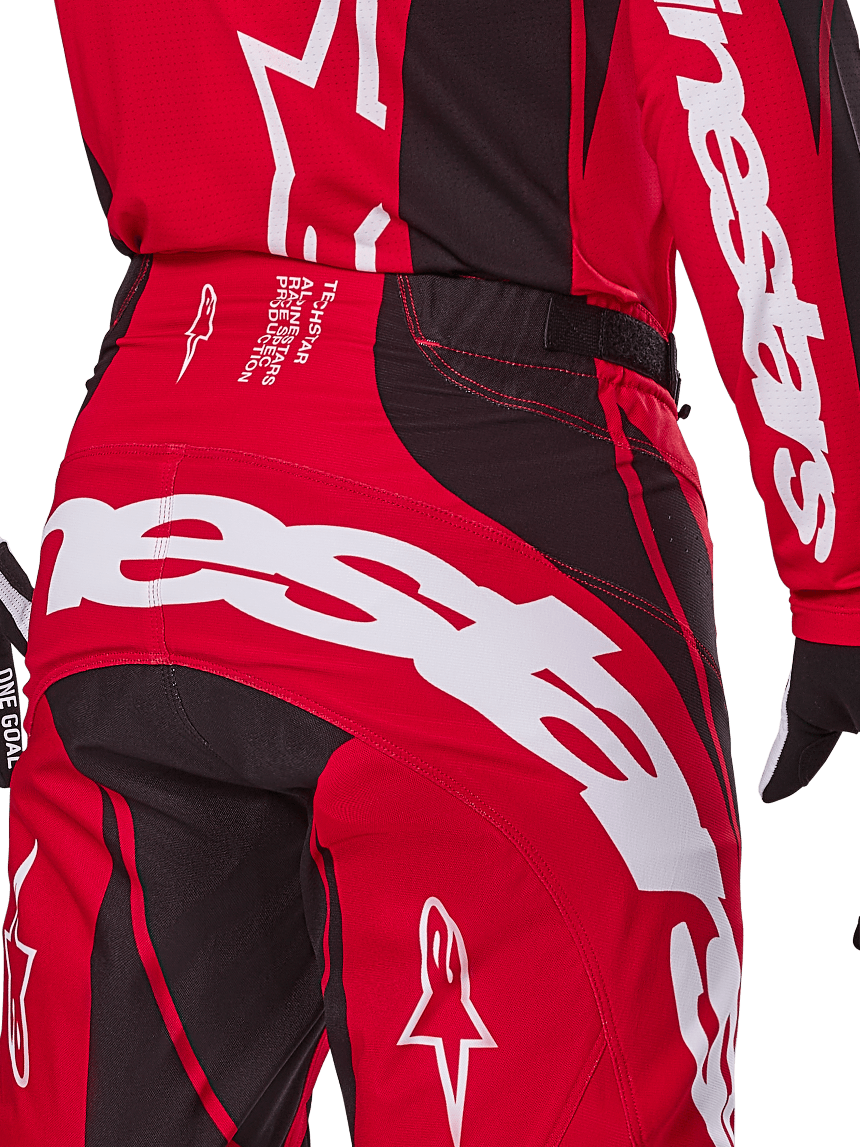Alpinestars 2025 Techstar Dreem Hose, Motocross-Hose, Hellrot und Schwarz, Nahaufnahme des hinteren Taillen- und Gesäßbereichs mit auffälligem weißem Alpinestars-Branding, schwarzen Stretch-Einsätzen und technischem Produktionstext am Bund, entwickelt für Performance im Offroad-Rennsport.
