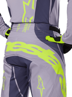 Alpinestars 2025 Techstar Dreem Hose, Motocross-Hose, Grau und Dunkelgrau mit leuchtend limonengrünen Akzenten, Rückansicht im Detail mit passendem Trikot und Handschuhen, großes neongelbes Branding am Gesäß, athletische Rennpassform für den Offroad-Sport