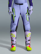 Alpinestars 2026 Supertech Scenz Hose, Motocross-Hose, Lila Gelb Fluo, mit großen neongelben Logos auf den Oberschenkeln, getragen mit passenden lila-gelben Motocross-Stiefeln und -Handschuhen, athletisches Performance-Design für den Offroad-Rennsport
