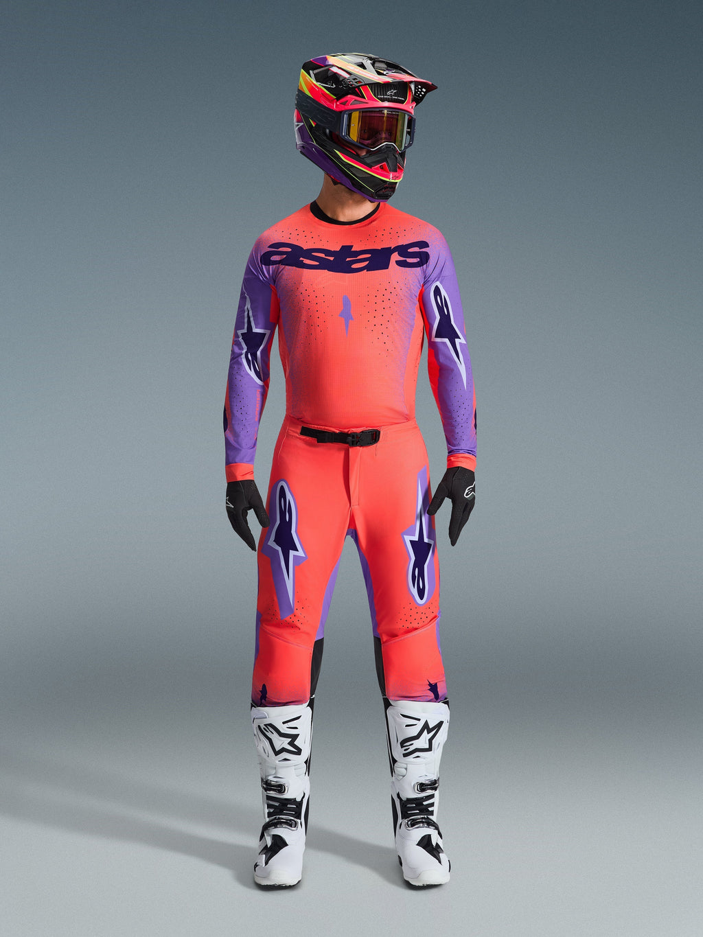 Alpinestars 2026 Supertech Scenz Pants, Motocross Pants, Hot Coral and Purple, worn as a complete gear set with matching jersey and helmet, white and black boots, featuring purple logos and athletic racing fit.