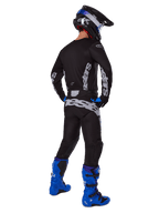 Alpinestars Pantalon Racer Graphite 2025, pantalon de motocross, noir et gris, vue arrière d'un pilote en équipement complet avec maillot assorti et bottes bleu vif, doté d'un grand marquage gris sur l'assise et d'une conception ergonomique pré-courbée pour la compétition tout-terrain