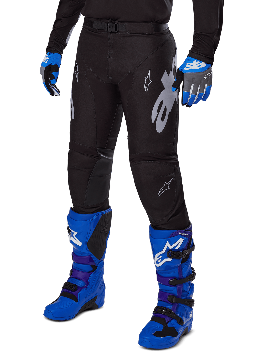 Pantalon Alpinestars Racer Graphite 2025, pantalon de motocross noir avec graphismes blancs et gris, porté avec des bottes de motocross bleu vif et des gants bleus assortis, tissu technique durable pour la conduite tout-terrain