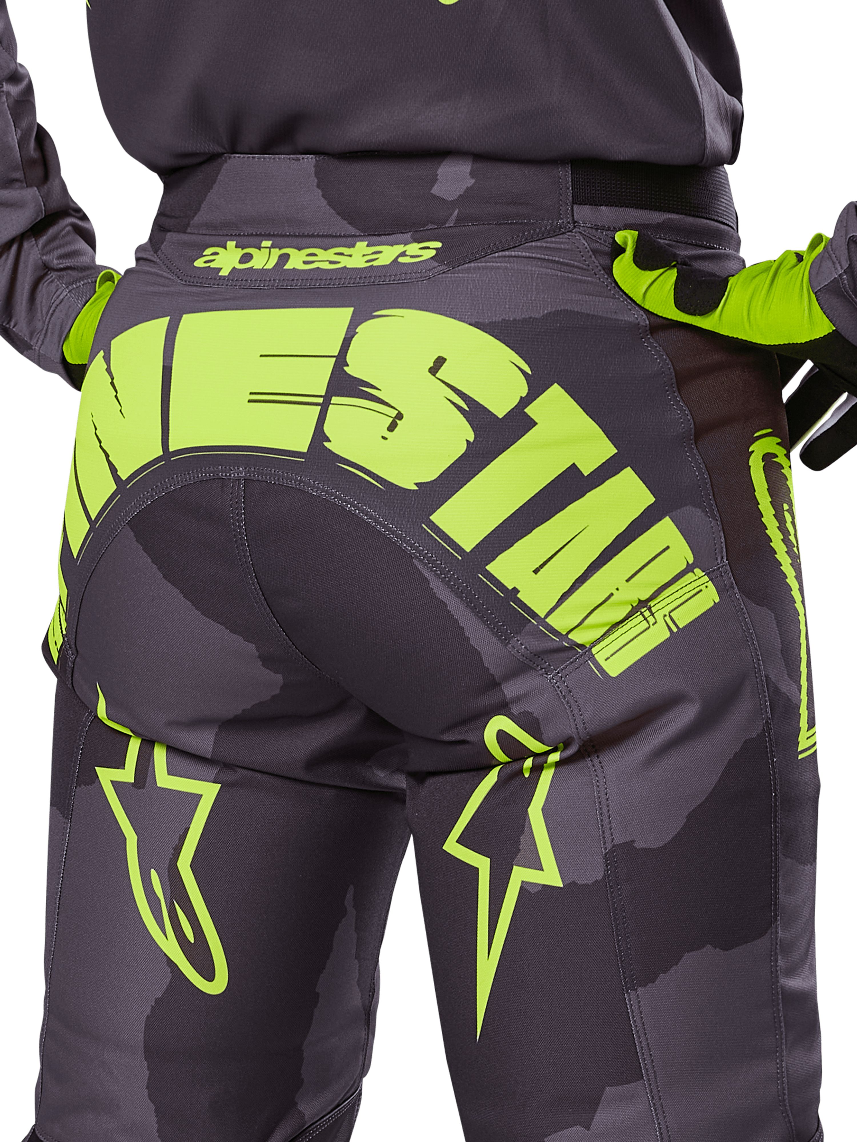Alpinestars 2025 Racer Hollow broek, motorcross broek, Dark Camo en fluorgeel, met een groot geel Alpinestars-logo op de achterkant, tactisch camouflagepatroon met felgele accenten en een duurzame constructie voor off-road racing.