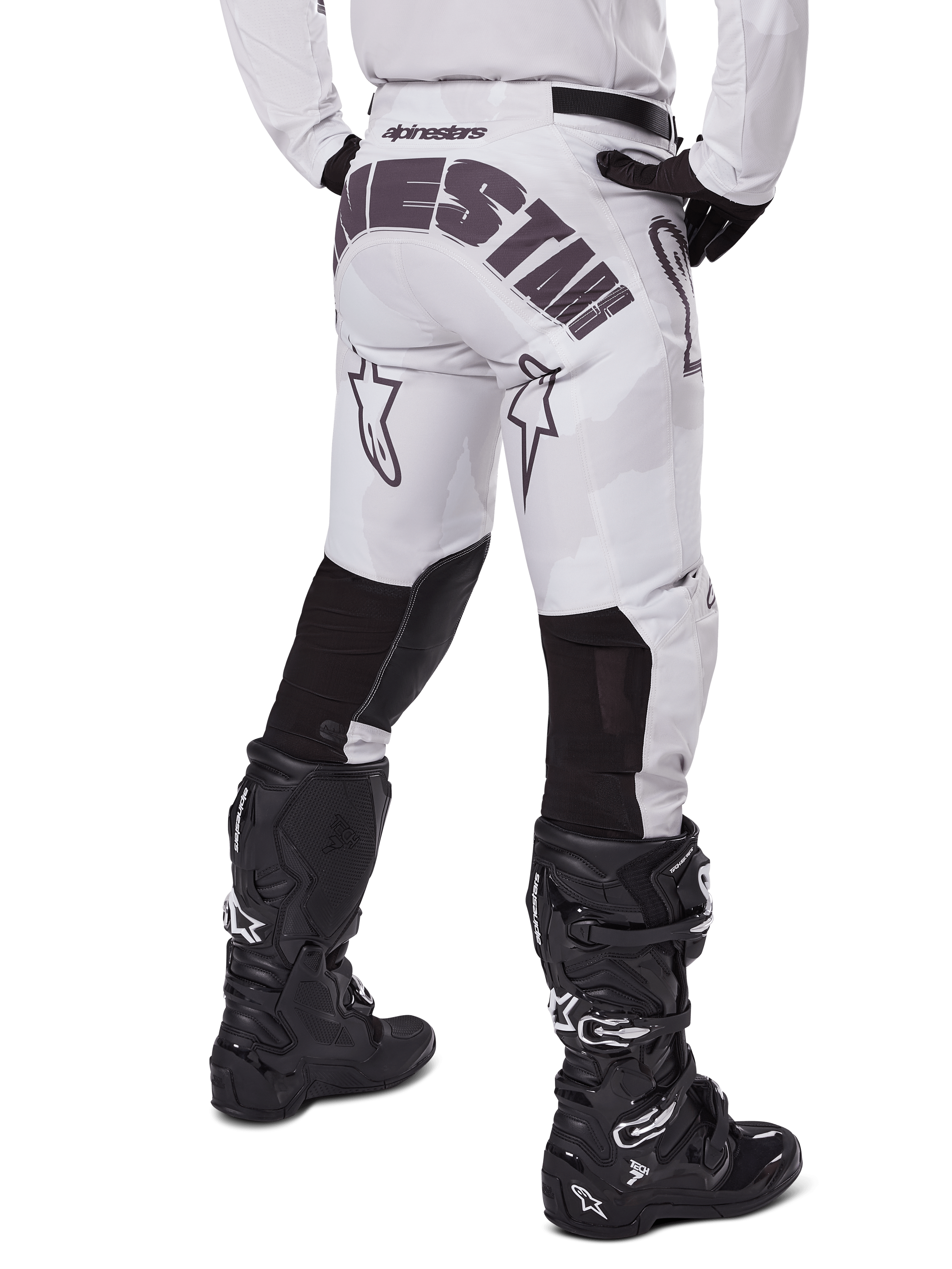 Alpinestars 2025 Racer Hollow Pants, motorcrossbroek, Light Camo Brown, achteraanzicht van de rijder met grote branding op het zitvlak en zwarte stretchpanelen op de onderbenen, gecombineerd met zwarte Tech 7 laarzen