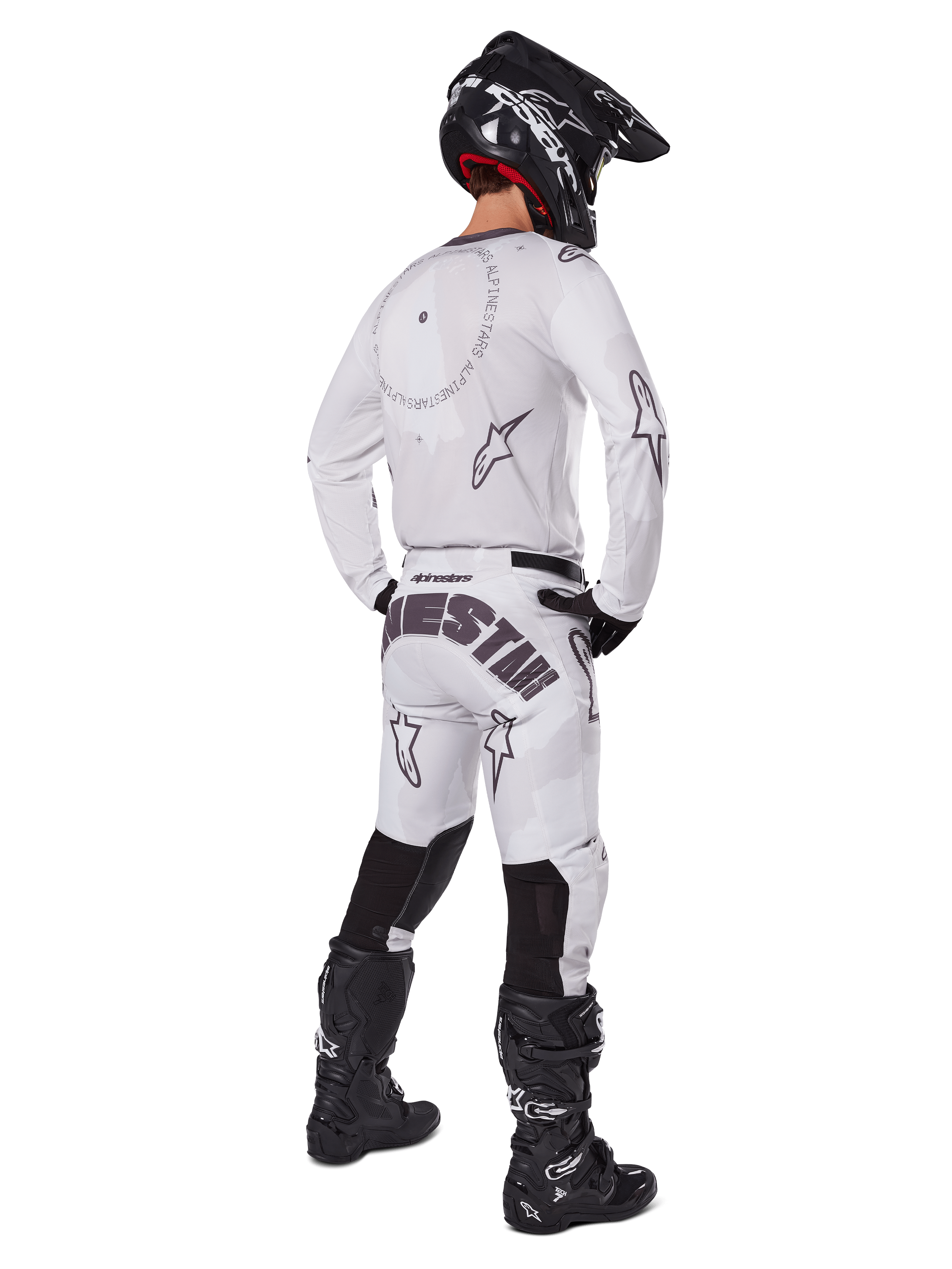 Alpinestars 2025 Racer Hollow Pants, motorcross broek, licht camo bruin en wit, achteraanzicht met opvallende zwarte branding op het zitvlak en sterlogo's, gedragen met bijpassende jersey, zwarte laarzen en een zwarte helm voor een complete off-road racing look