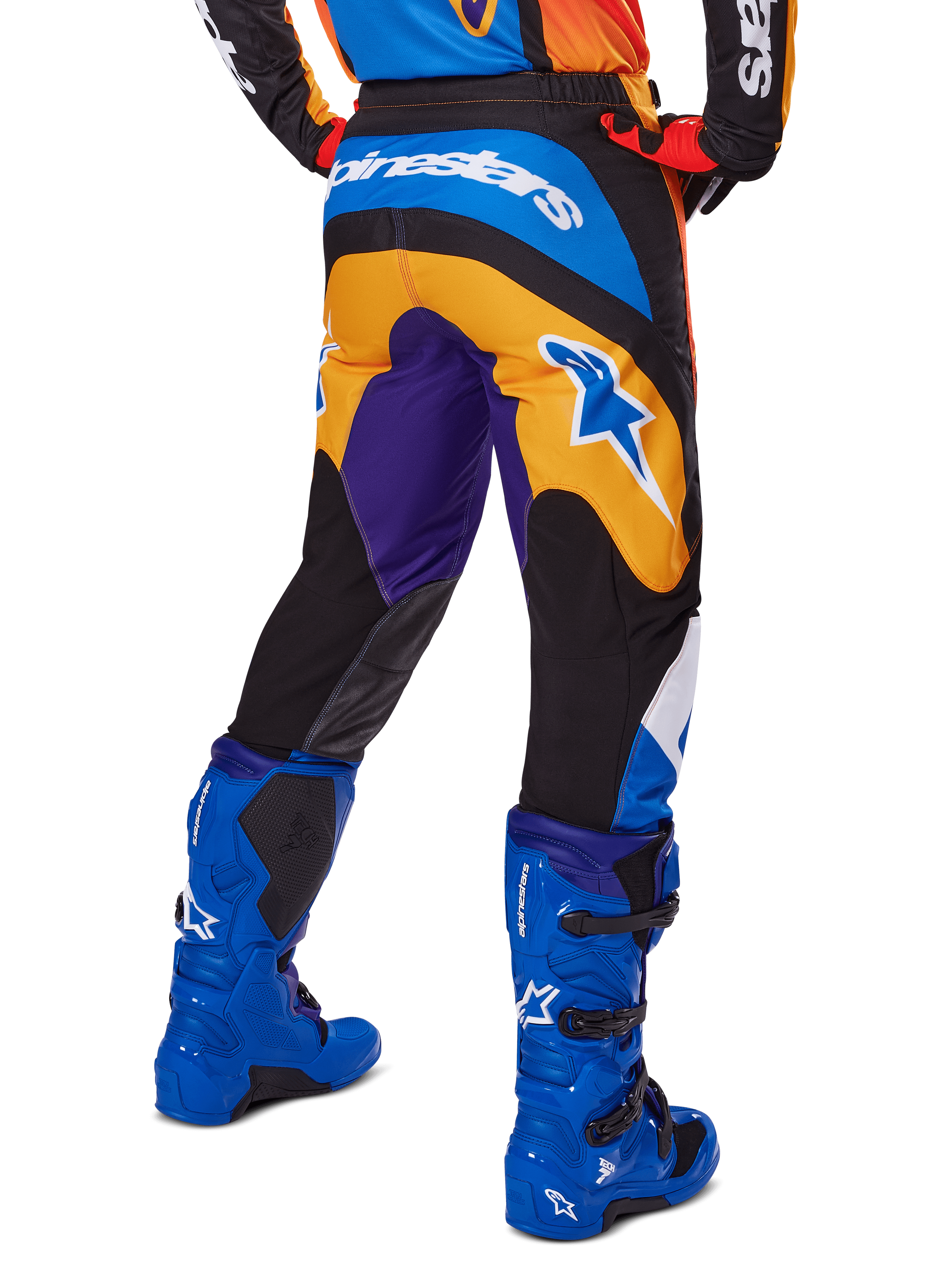 Alpinestars 2025 Fluid Wurx Hose, Motocross-Hose, Mehrfarbig mit Orange, Lila und Blau, Rückansicht mit weißem Alpinestars-Logo auf der Rückseite, kombiniert mit blauen Motocross-Stiefeln, sportliche Passform für Offroad-Rennsport