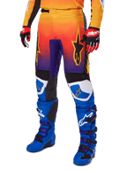 Alpinestars 2025 Fluid Wurx Hose, Motocross-Hose, mehrfarbiger Farbverlauf in Orange, Rot und Lila mit schwarzen und blauen Einsätzen, getragen mit blauen Stiefeln und roten Handschuhen, mit Stern-Logo-Grafiken und weißen Knie-Akzenten, strapazierfähige Performance-Ausrüstung für Offroad-Rennsport