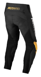 Alpinestars Techstar Quadro Pants, motorcrossbroek, zwart met geel en tangerine, achteraanzicht met gele 'ASTARS' branding op de tailleband, zwarte mesh-inzetstukken voor ventilatie en ergonomische geel en tangerine kniepanelen voor duurzaamheid tijdens off-road racen.