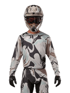 Alpinestars 2024 Racer Tactical Jersey, maillot de motocross, motif camouflage Iron Camo Dust Gray, pilote portant un casque et des lunettes assortis avec des gants noirs, équipement technique pour la course tout-terrain