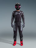 Ensemble Alpinestars 2026 Fluid Apex, tenue de motocross, noir avec accents gris, maillot arborant un grand logo Astars blanc, pantalon assorti avec un marquage imposant, casque noir avec lunettes roses et bottes rouge vif, kit complet de course tout-terrain
