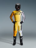 Alpinestars 2026 Fluid Apex motorcrossset, volledig motorcrosspak met geel, oranje en wit kleurverloop op de jersey en broek, gecombineerd met een zwarte helm, bril en laarzen, opvallend zwart logo op de borst, complete off-road racebescherming