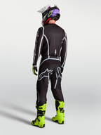 Alpinestars Fluid Apex V2 broek, heren motocrossbroek, zwart en zilver, achteraanzicht met jersey en neon motorlaarzen.