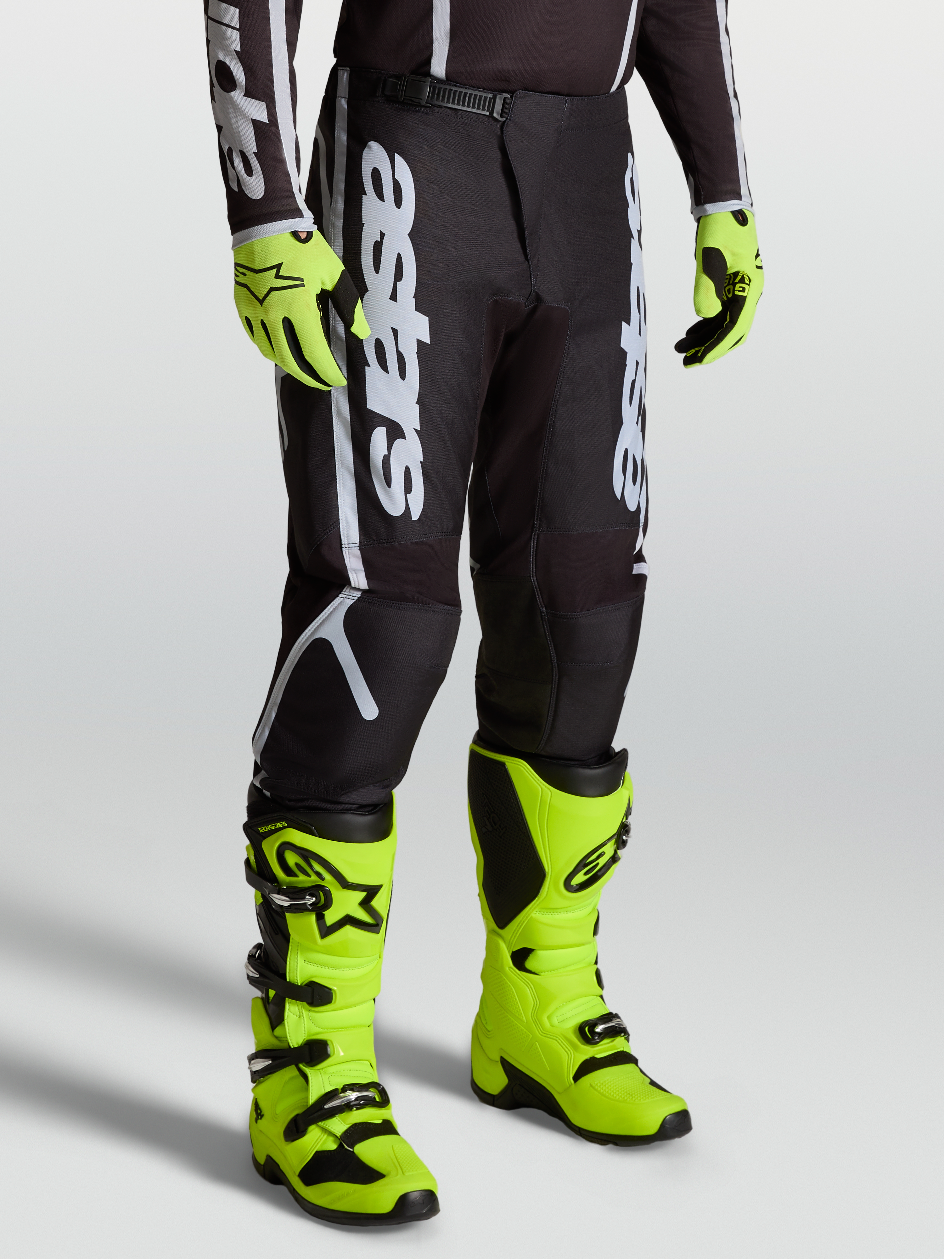 Alpinestars Fluid Apex V2 Pants, Men’s Motocross Gear in Black and Silver, featuring Alpinestars branding and durable 600D polyfabric. Shown on-model with bright yellow boots.