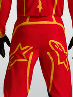 Alpinestars Fluid Apex V2 broek, motocrossbroek in rood en goud, met versterkt rugpand en grote ster-graphics op het zitvlak.