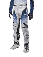 Alpinestars 2024 Racer Hoen Pants, pantalon de motocross, blanc, bleu marine et bleu clair avec logos blancs, équipement de protection haute performance pour tout-terrain, porté avec gants et bottes de motocross.