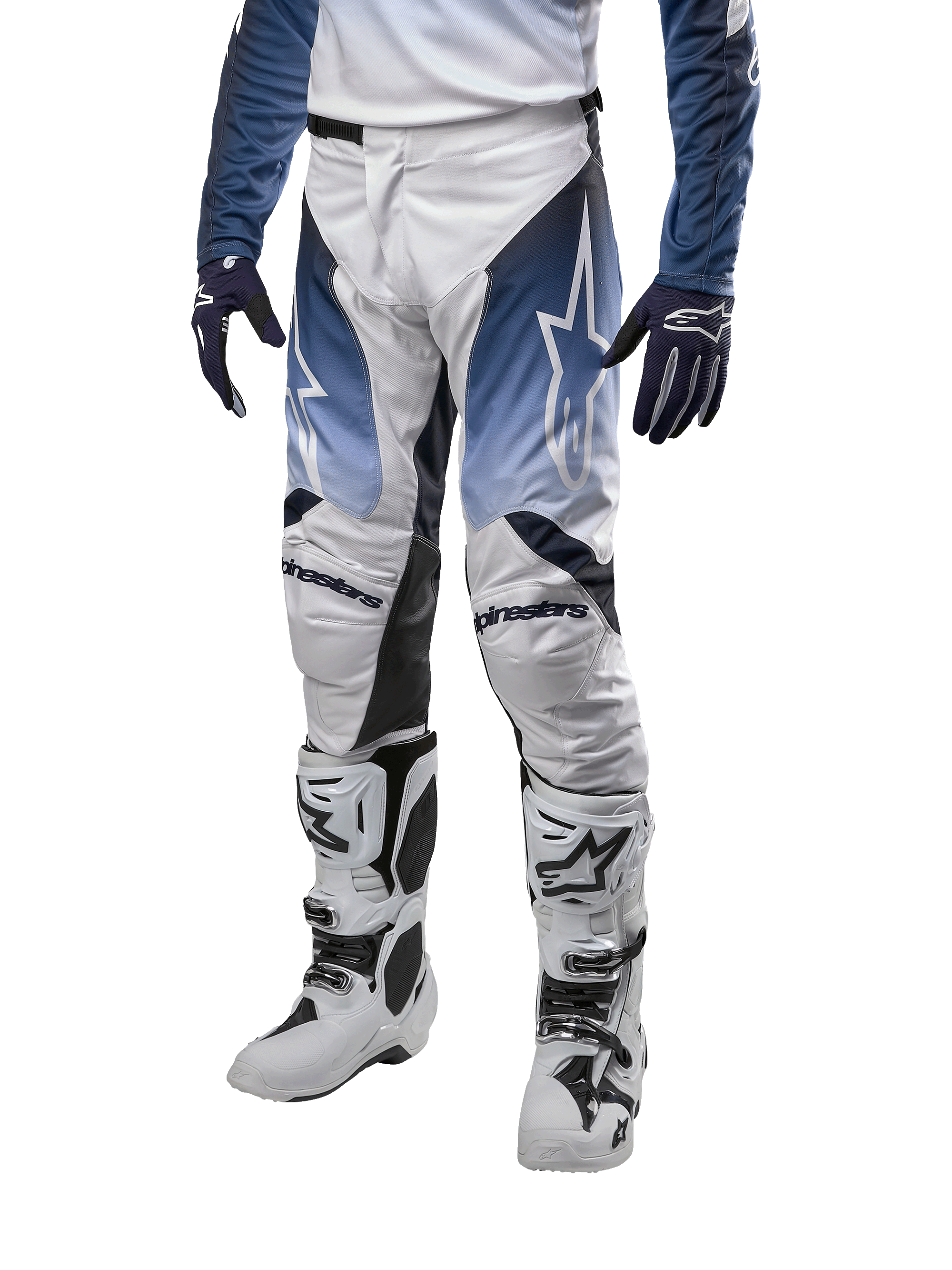 Alpinestars 2024 Racer Hoen Pants, pantalon de motocross, blanc, bleu marine et bleu clair avec logos blancs, équipement de protection haute performance pour tout-terrain, porté avec gants et bottes de motocross.