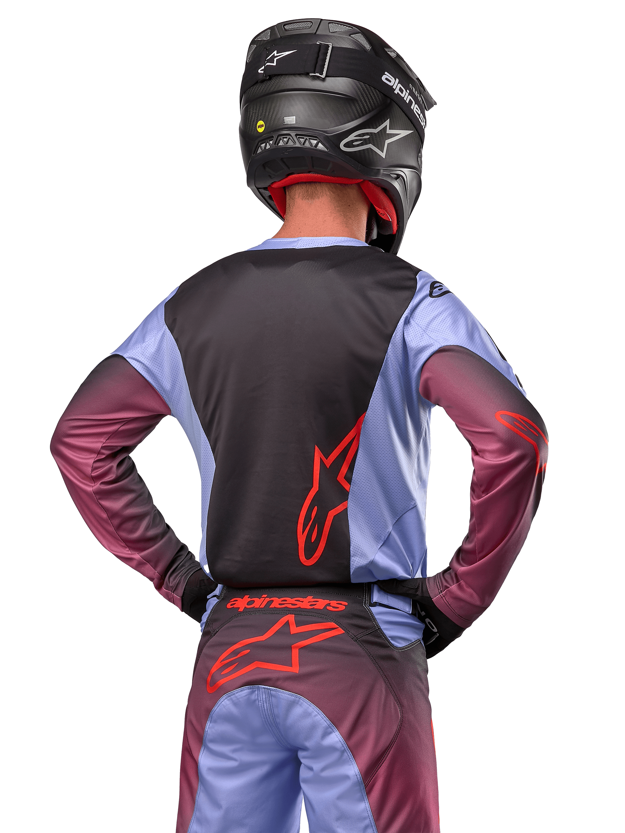 Motorcrossrijder van achteren in Alpinestars 2024 Racer Hoen uitrusting, Lavan Purple en zwart jersey met rood logo, bijpassende broek met rode accenten, zwarte helm, gecoördineerde outfit voor off-road racen