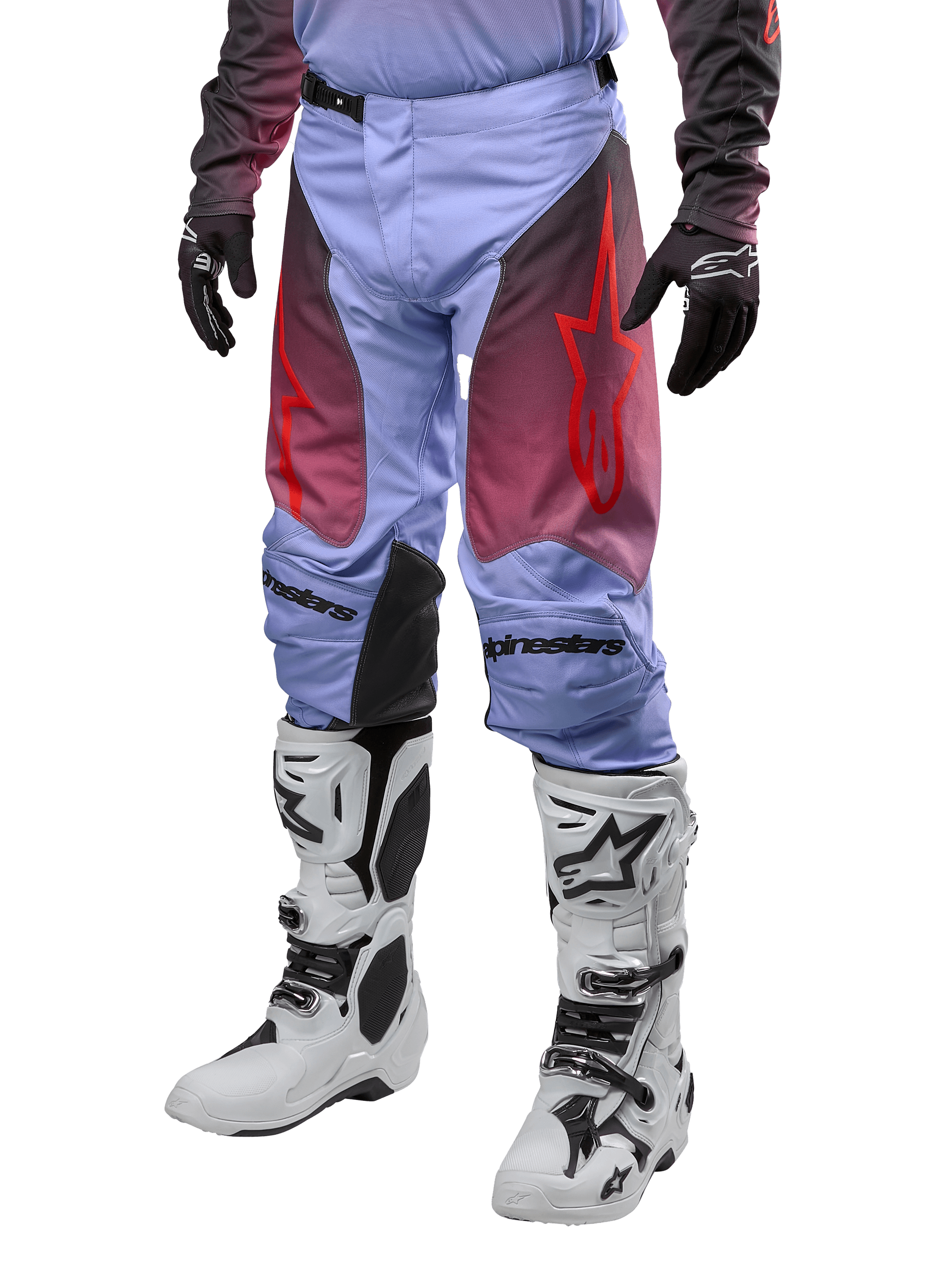 Alpinestars 2024 Racer Hoen Hose, Motocross-Hose, Lavan-Lila und Schwarz mit roten Grafiken, rote Stern-Logos auf den Oberschenkeln und schwarzer Schriftzug an den Knien, getragen mit weiß-schwarzen Stiefeln und schwarzen Handschuhen