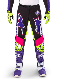 Alpinestars Limited Edition Supertech Dirt Studios Hose, Motocross-Hose, Weiß, Lila und Neongelb, mit schwarzen Einsätzen sowie neongelben und pinken Akzenten, große lila Stern-Logos, abgebildet mit passenden neongelben Handschuhen und lila Rennstiefeln, strapazierfähige Offroad-Rennbekleidung
