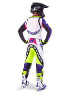 Motocross-Fahrer in Alpinestars Limited Edition Supertech Dirt Studios® Hose in Weiß, Lila und Gelb Fluo, Rückansicht mit passendem Trikot, Stiefeln und schwarzem Carbon-Helm, professionelle Offroad-Rennausrüstung mit markanten Grafiken und Neon-Akzenten.