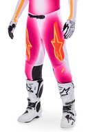 Alpinestars Supertech AFD MIG Limited Edition Motocross-Hose, Pink mit orangefarbenen und gelben Stern-Logos, getragen mit weißen Motocross-Stiefeln und schwarz-weißen Handschuhen, mit schwarzen Knie-Innenpaneelen und einer athletischen Passform, Teil eines Hochleistungs-Rennausrüstungs-Sets