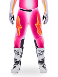 Alpinestars Limited Edition Supertech AFD MIG Hose, Motocross-Rennhose, Pink Fluo und Weiß mit orangen Akzenten, mit großen Stern-Logos auf den Oberschenkeln, perforierten Einsätzen und schwarzen Knie-Grip-Zonen, getragen mit weiß-schwarzen Motocross-Stiefeln