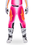 Alpinestars Limited Edition Supertech AFD MIG Hose, Motocross-Rennhose, Pink Fluo und Weiß mit orangen Akzenten, mit großen Stern-Logos auf den Oberschenkeln, perforierten Einsätzen und schwarzen Knie-Grip-Zonen, getragen mit weiß-schwarzen Motocross-Stiefeln