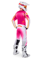 Motocross-Fahrer in der Rückansicht, Limited Edition Supertech AFD MIG Gear Set, pinkes Trikot mit orangefarbenen Akzenten, weiße Hose mit pinkem Farbverlauf und orangefarbenem Alpinestars-Branding, weißer Helm mit pinken Grafiken und orangefarbener Brille, weiß-schwarze Stiefel, professionelle Offroad-Rennausrüstung