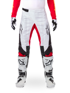 Alpinestars Limited Edition Techstar Deep Hose, Motocross-Hose, Schwarz, Weiß und High Red, getragen mit passendem rotem Jersey, weiß-schwarzen Handschuhen und Stiefeln, mit weißen Frontpanels, roten Akzenten an den Beininnenseiten, schwarzen Seitenpanels, Alpinestars-Logos auf den Oberschenkeln und laserperforierten Details zur Belüftung.