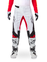 Alpinestars Limited Edition Techstar Deep crossbroek, motorcrossbroek, zwart, wit en felrood, gedragen met bijpassende rode jersey, witte en zwarte handschoenen en laarzen, voorzien van witte voorpanelen, rode accenten aan de binnenkant van de benen, zwarte zijpanelen, Alpinestars-logo's op de dijen en laser-geperforeerde details voor ventilatie.