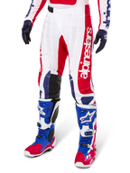 Alpinestars Limited Edition Techstar Fortitude Hose, Motocross-Hose, Hellrot, Weiß und Blau, getragen mit passenden Offroad-Stiefeln und Handschuhen, mit vertikalem Branding am Bein, atmungsaktiven perforierten Einsätzen und schwarzen verstärkten Kniepartien, athletisches Race-Fit-Design