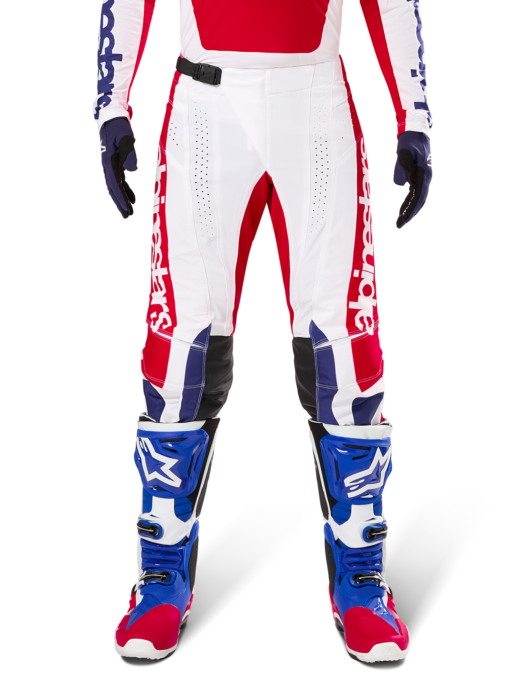 Alpinestars Limited Edition Techstar Fortitude Hose, Motocross-Hose, Hellrot, Weiß und Blau, getragen mit passender Ausrüstung einschließlich blauer Schutzstiefel und Handschuhe, weißes Chassis mit roten Grafiken, schwarze Leder-Knieeinsätze und lasergeschnittene Perforationen, professionelle Offroad-Rennbekleidung