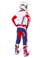 Alpinestars Limited Edition Techstar Fortitude Hose, Motocross-Hose, Hellrot, Weiß und Blau, in der Rückenansicht an einem Fahrer mit passendem Trikot, Stiefeln und Helm dargestellt, hebt die athletische Passform und die markante Logoplatzierung hervor.