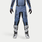 Pantalon Alpinestars Fluid Lurv 2024, pantalon de motocross, bleu clair et noir, porté avec des bottes de course blanches et noires et des gants assortis, arborant des logos étoiles noirs sur les cuisses, conception ergonomique pour la performance tout-terrain