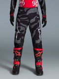 Alpinestars Beperkte Oplage Techstar Beast Coast broek, motorcrossbroek voor off-road, zwart en oranje met camouflagepatroon, gedragen door een model.