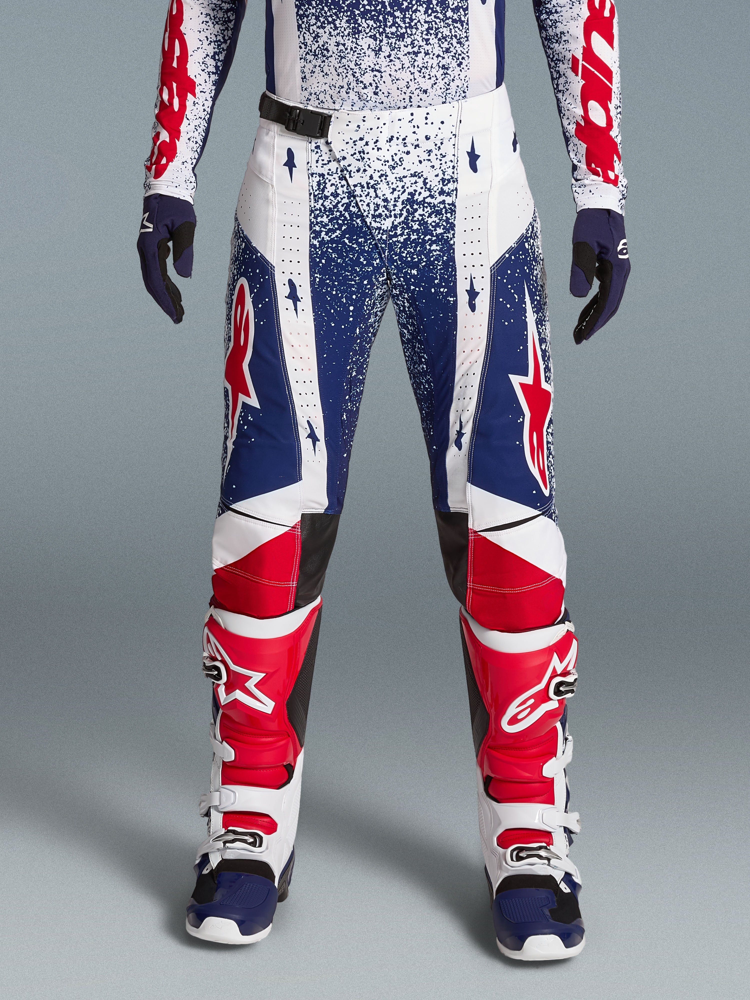 Alpinestars Techstar Unity beperkte oplage kledingset, rood, wit en blauw gespikkelde motorcrossbroek met motorlaarzen.