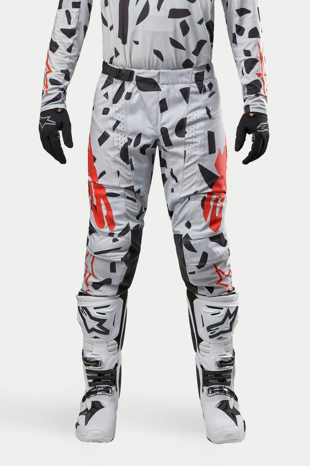Pantalon Alpinestars Techstar Rantera 2024, pantalon de motocross, Haze Gray Camo, porté avec un maillot assorti, des gants noirs et des bottes blanches, avec des motifs à taches noires et logos Alpinestars rouges, conception durable pour la course tout-terrain