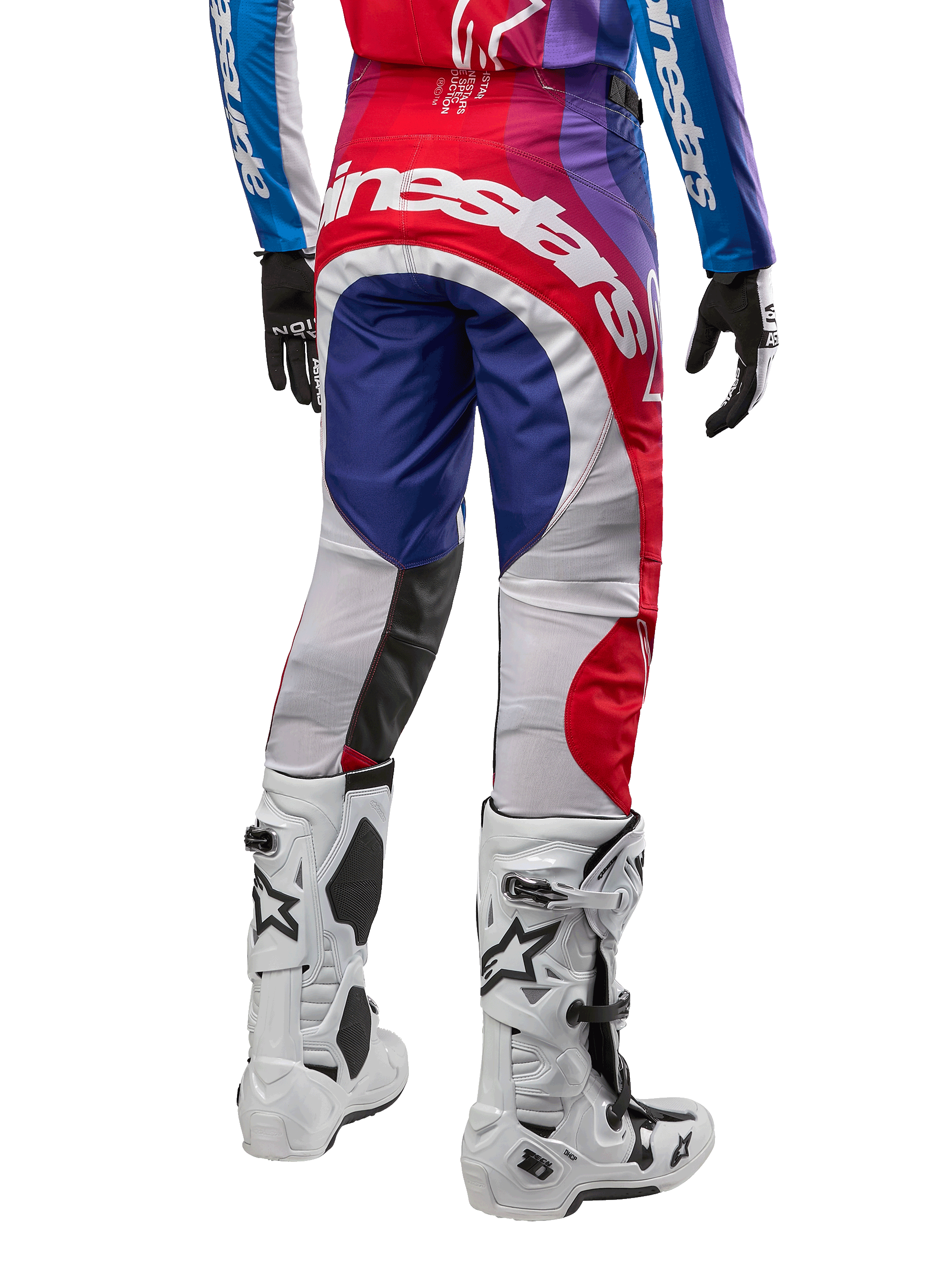 Alpinestars 2024 Techstar Pneuma crossbroek, motorcrossbroek, blauw mars rood wit, achteraanzicht gedragen met bijpassende jersey en witte laarzen, met opvallende witte branding op het zitvlak en veelkleurige panelen, professionele motorcross racekleding