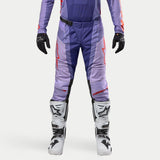 Alpinestars 2024 Techstar Ocuri Pants, pantalon de motocross, violet avec accents orange vif et logos rouges, porté avec des bottes de motocross blanches et des gants noirs, équipement technique durable.