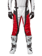Pantalon Alpinestars Techstar Ocuri 2024, pantalon de motocross, rouge Mars, blanc et noir, vue de face porté avec un maillot blanc assorti, des gants noirs et des bottes blanches, doté de panneaux perforés respirants et d'une coupe inspirée de la course pour des performances tout-terrain.