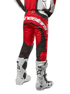 Pantalon Alpinestars Techstar Ocuri 2024, pantalon de motocross, rouge Mars, blanc et noir, vue arrière avec grand logo Alpinestars blanc sur l'assise, panneaux de ventilation en mesh noir, porté avec des bottes de motocross blanches et noires, coupe athlétique pour le pilotage tout-terrain