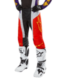 Alpinestars 2024 Techstar Ocuri crossbroek, motorcross racingbroek, feloranje, zwart en wit met geel sterrendesign, gedragen met paarse jersey en witte laarzen, duurzame performance kleding voor off-road competitie